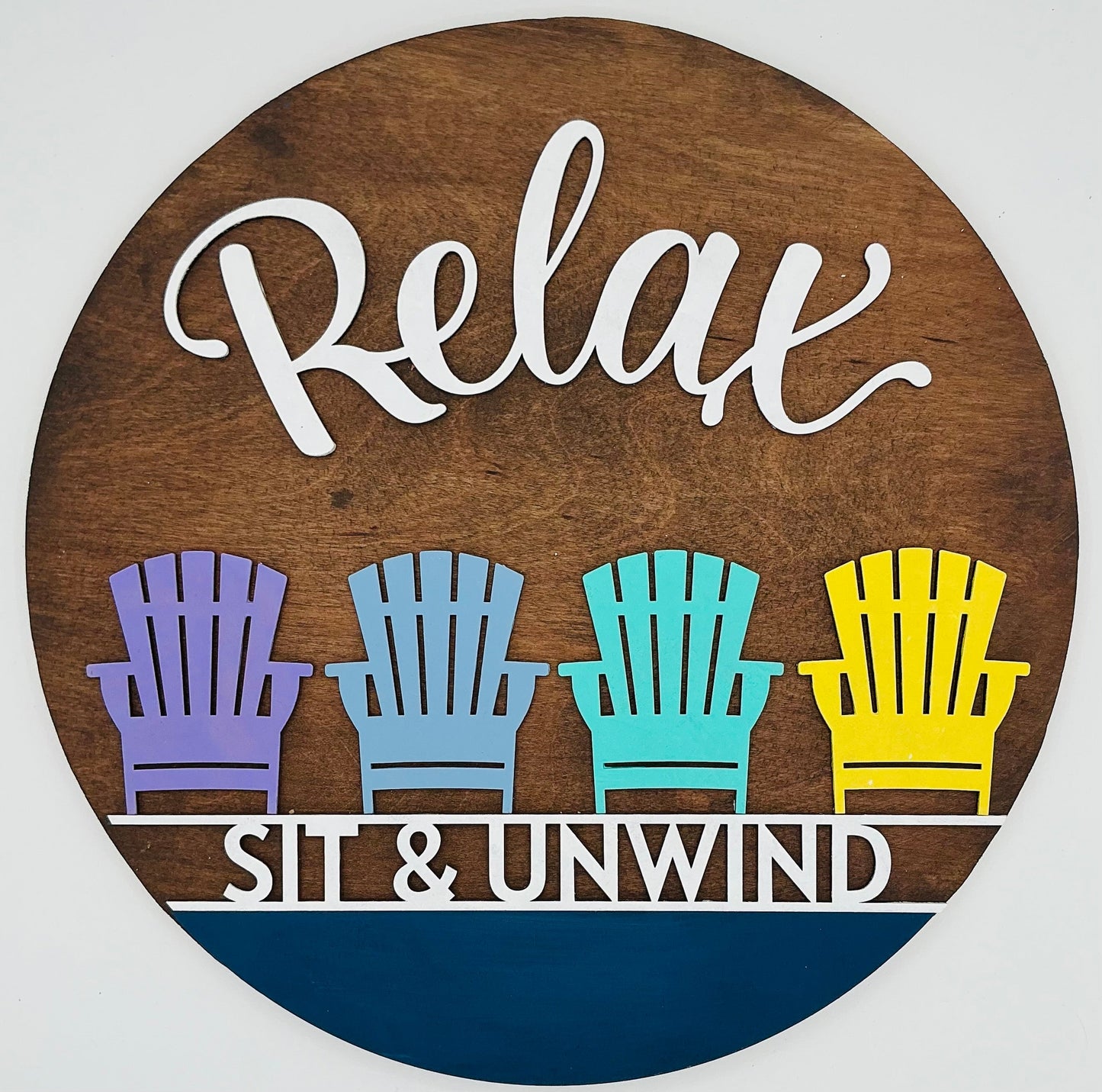 Decorative sign with 'Relax Sit & Unwind' text and colorful chairs on a wooden background.