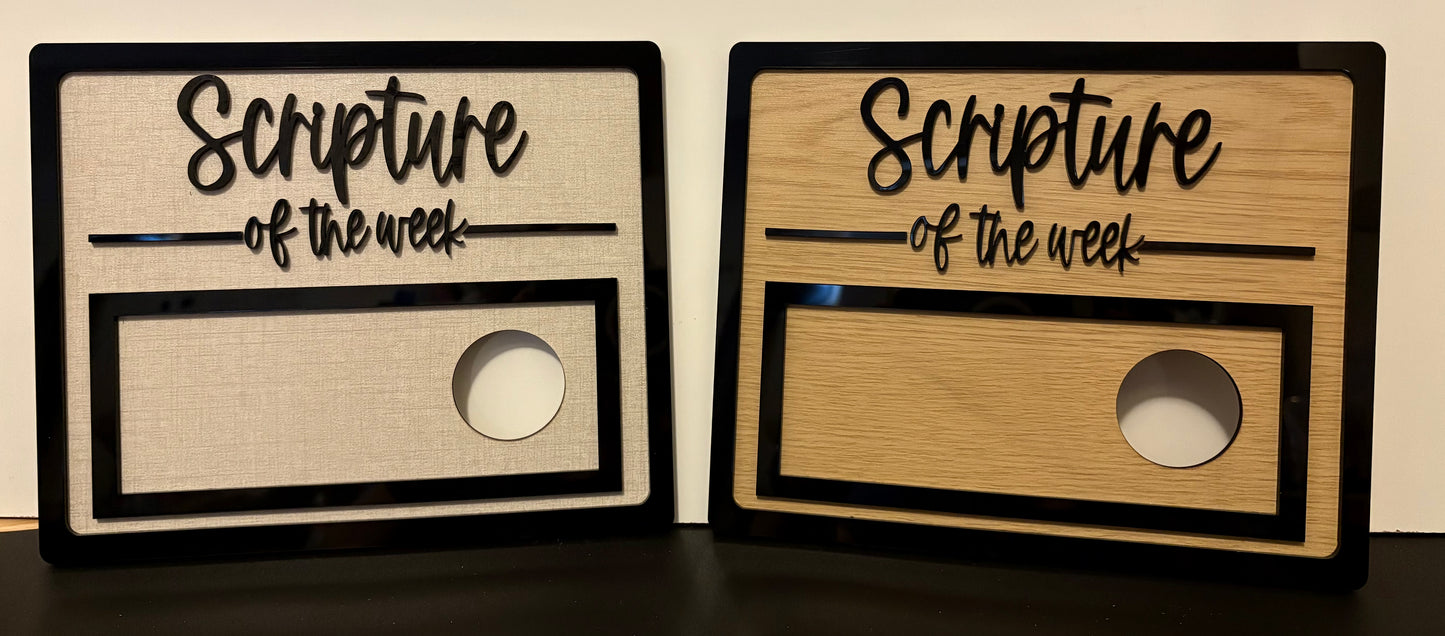 Two wooden signs with 'Scripture of the week' text on a dark surface.