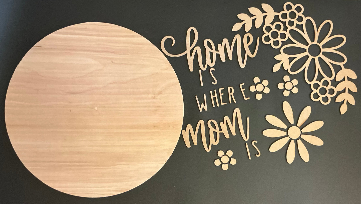Wooden cutout with 'home is where mom is' text and floral designs on a dark background