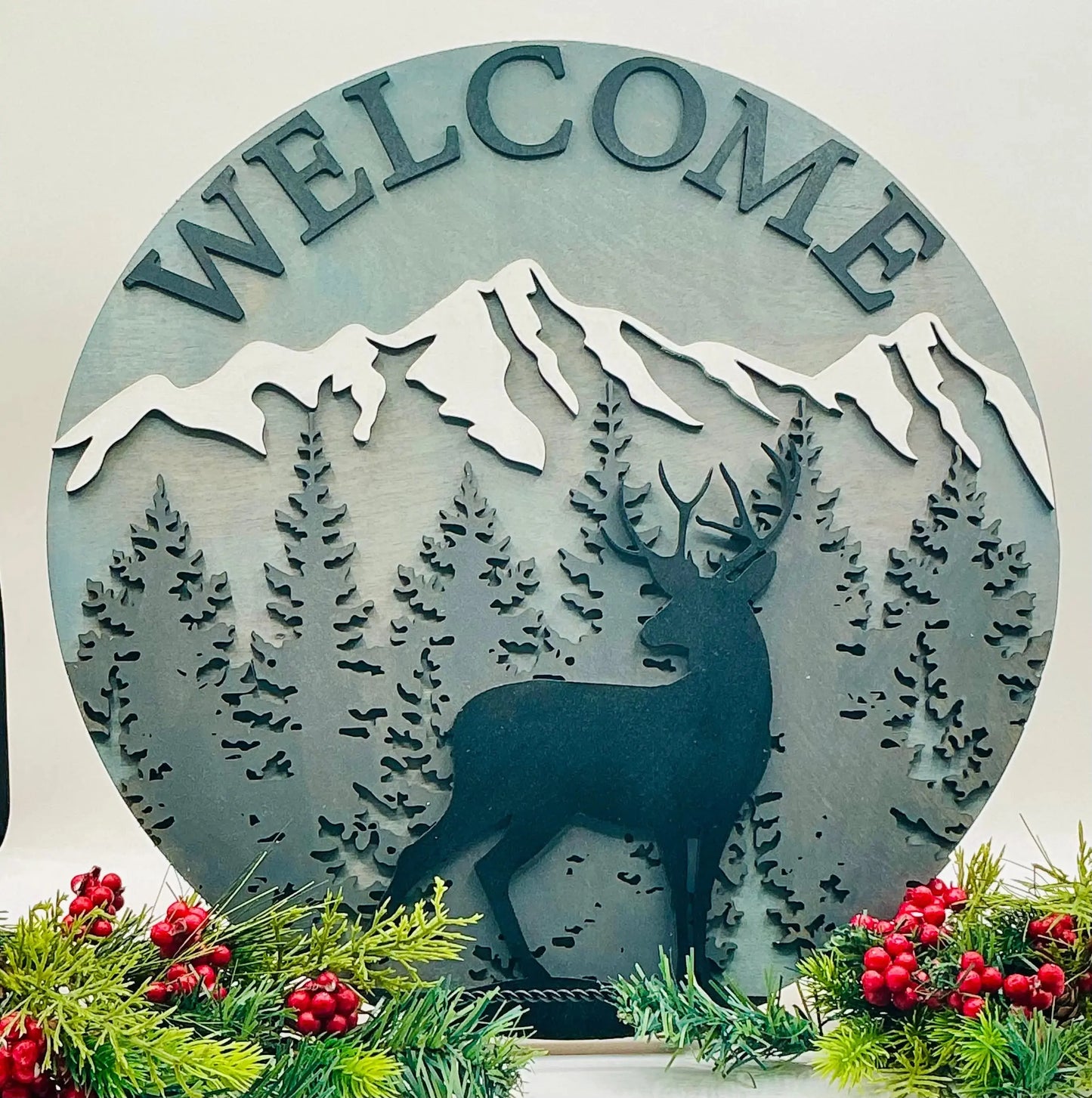 Decorative metal sign with 'WELCOME' and deer design, surrounded by Christmas decorations.