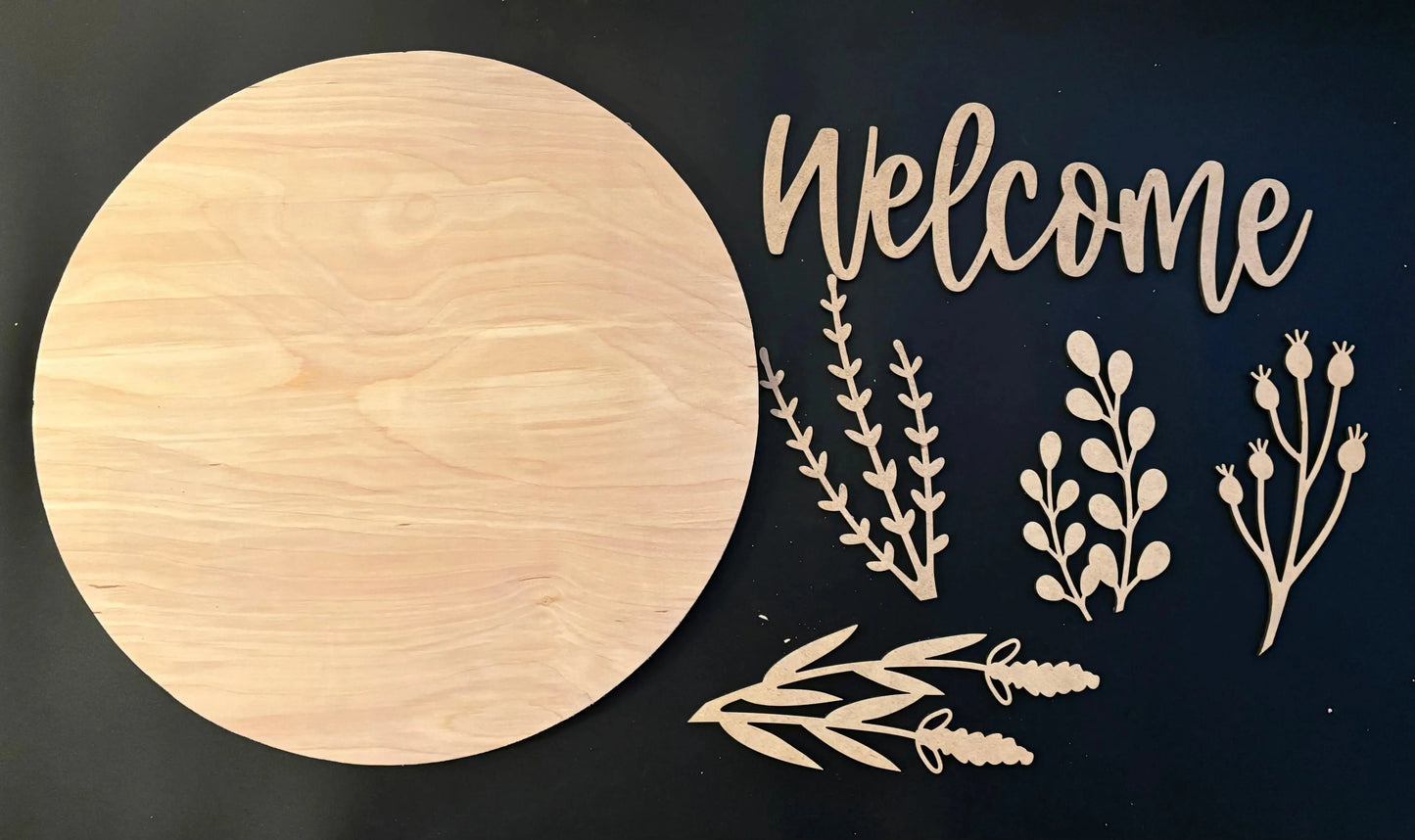 Wooden round board with 'Welcome' and floral cutouts on a black background