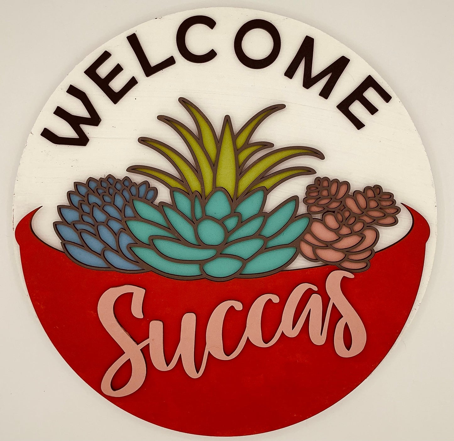 Decorative sign with succulents and 'Welcome Succas' text on a white background