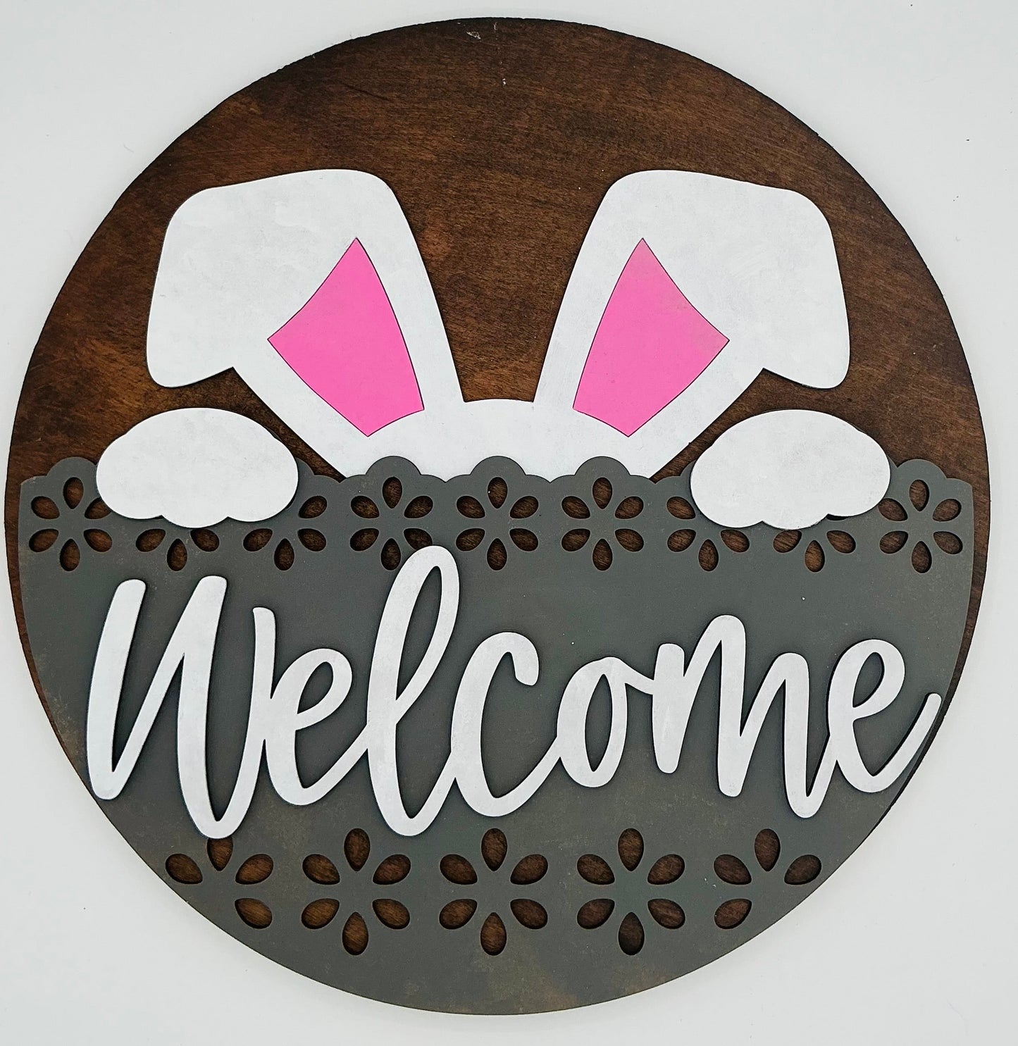 Decorative sign with bunny ears and 'Welcome' text on a wooden background