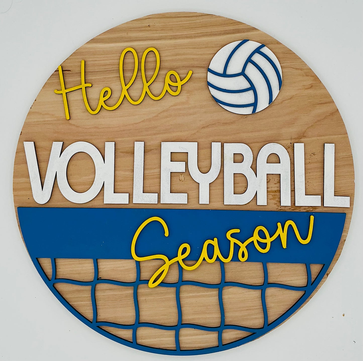 A circular decorative plaque with a volleyball design, featuring the text 'Hello Volleyball Season' in a stylized font, a volleyball image, and a net design.