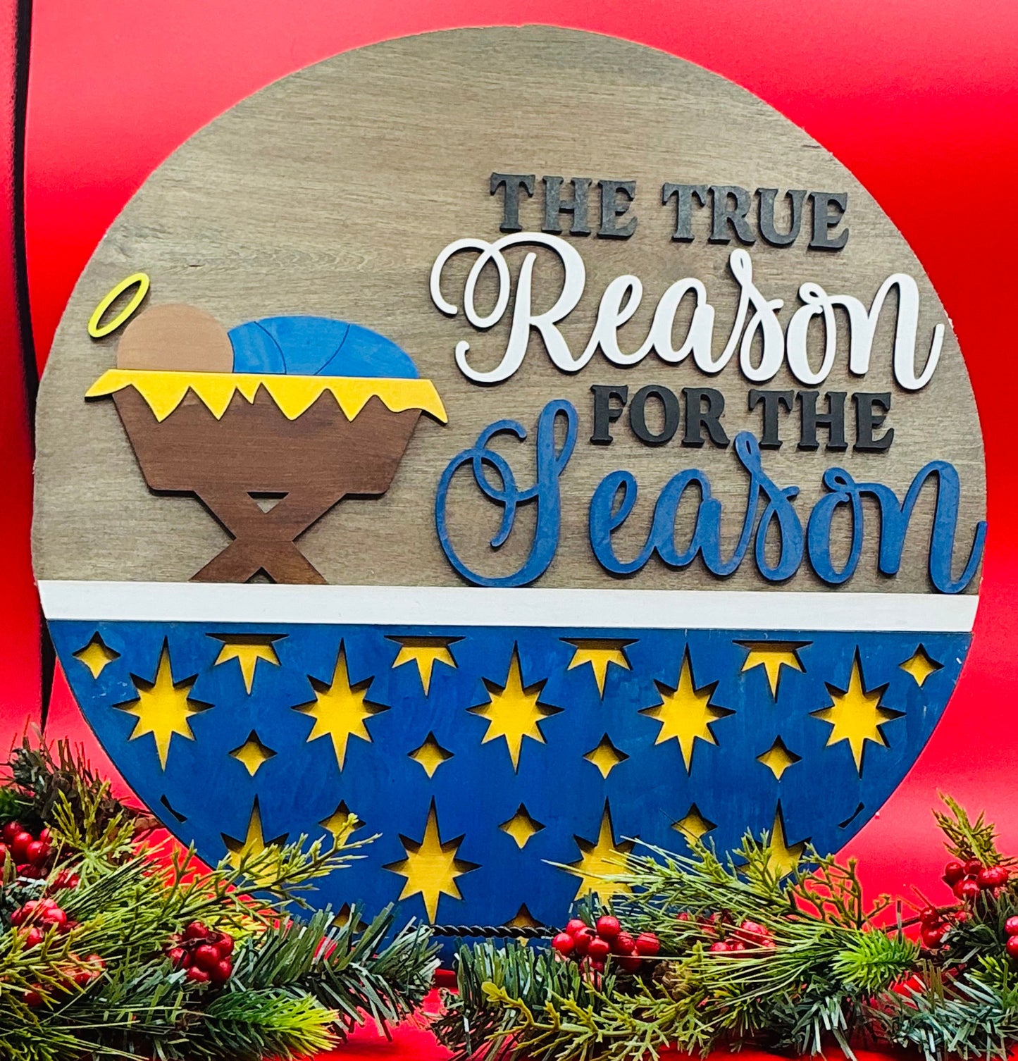 Decorative sign with nativity scene and 'The True Reason for the Season' text on a red background.