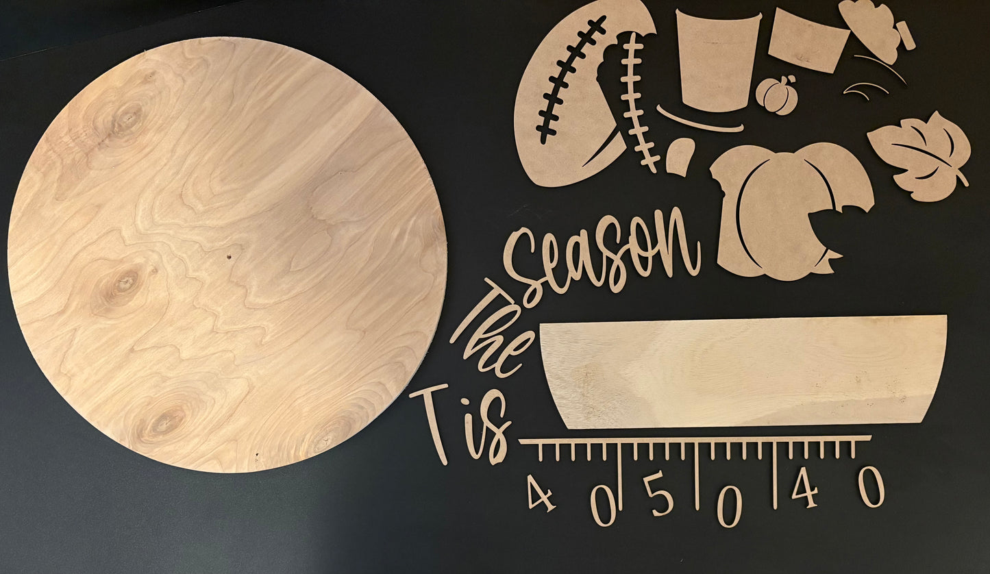 Wooden cutouts with 'Tis the season' text and various shapes on a dark background