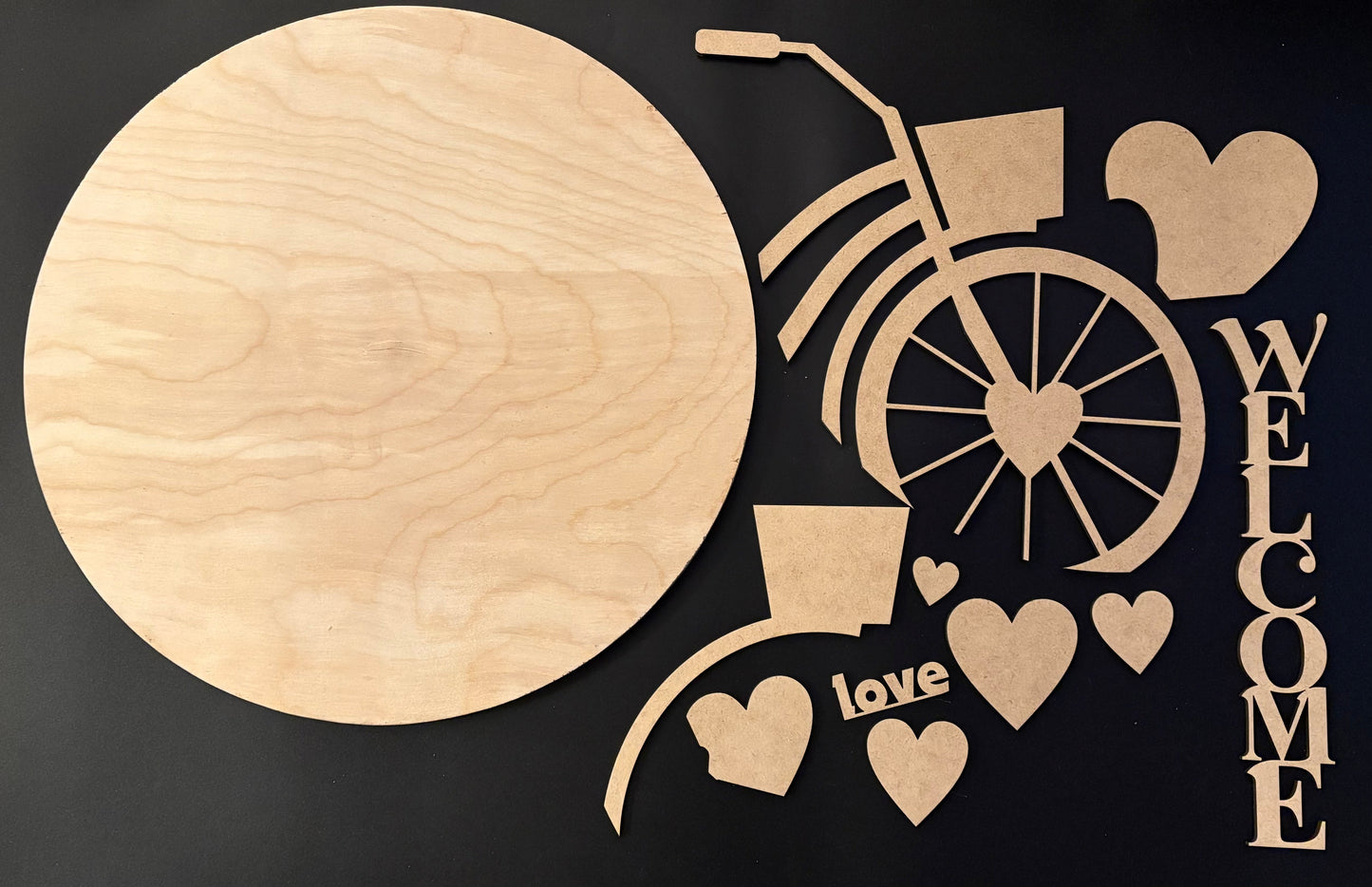 Wooden cutout of a bicycle with hearts and 'Welcome' text on a black background