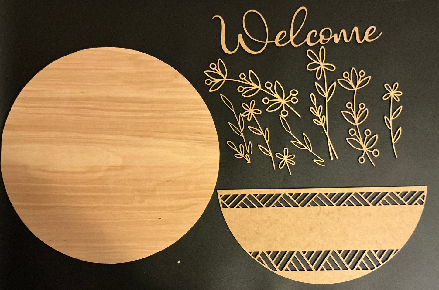 Decorative wooden cutouts with floral design and 'Welcome' text on a black background