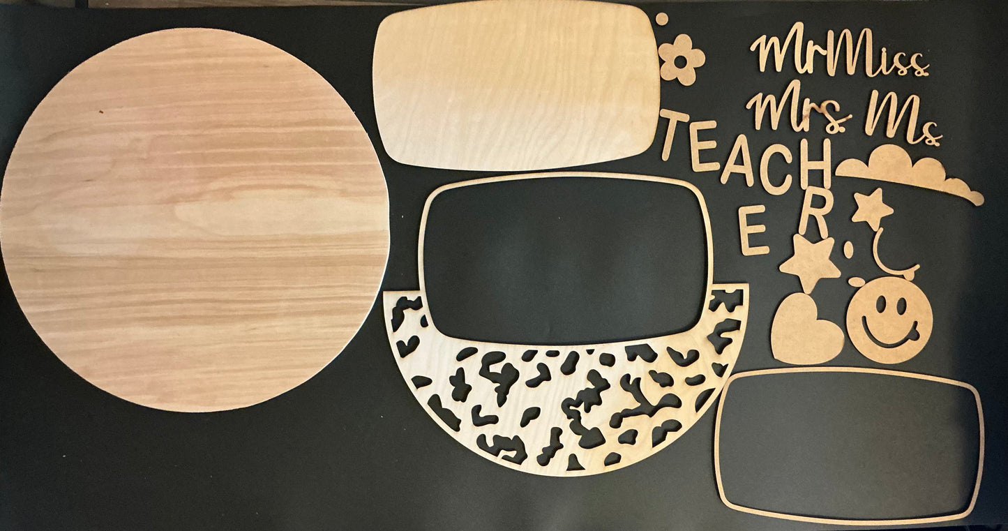 Wooden cutouts of a teacher's hat with decorative elements on a black background