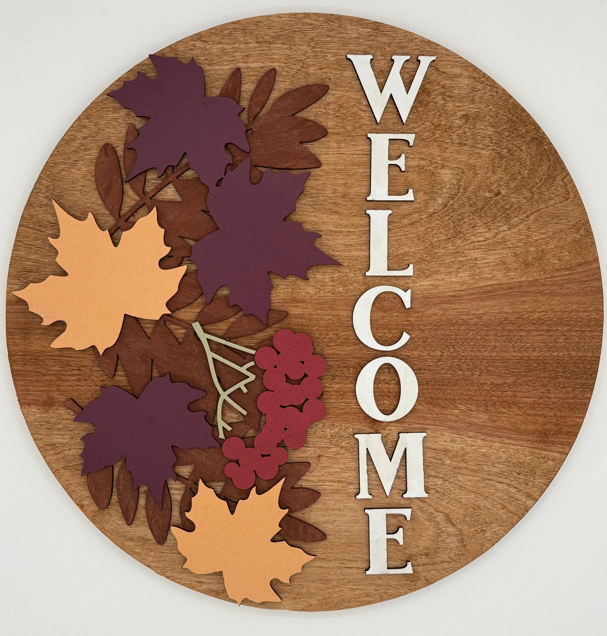Wooden round sign with autumn leaf designs and 'WELCOME' text on a white background