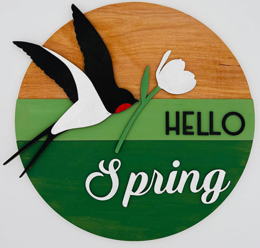 Decorative sign with a bird, flower, and 'Hello Spring' text on a wooden background