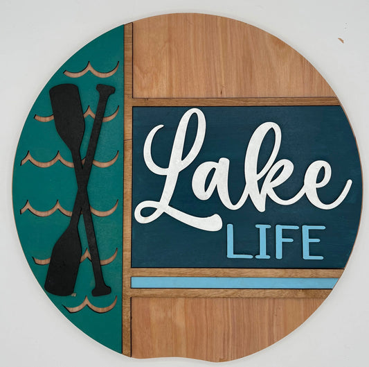 Decorative sign with 'Lake Life' text and paddle design on a teal and wooden background.