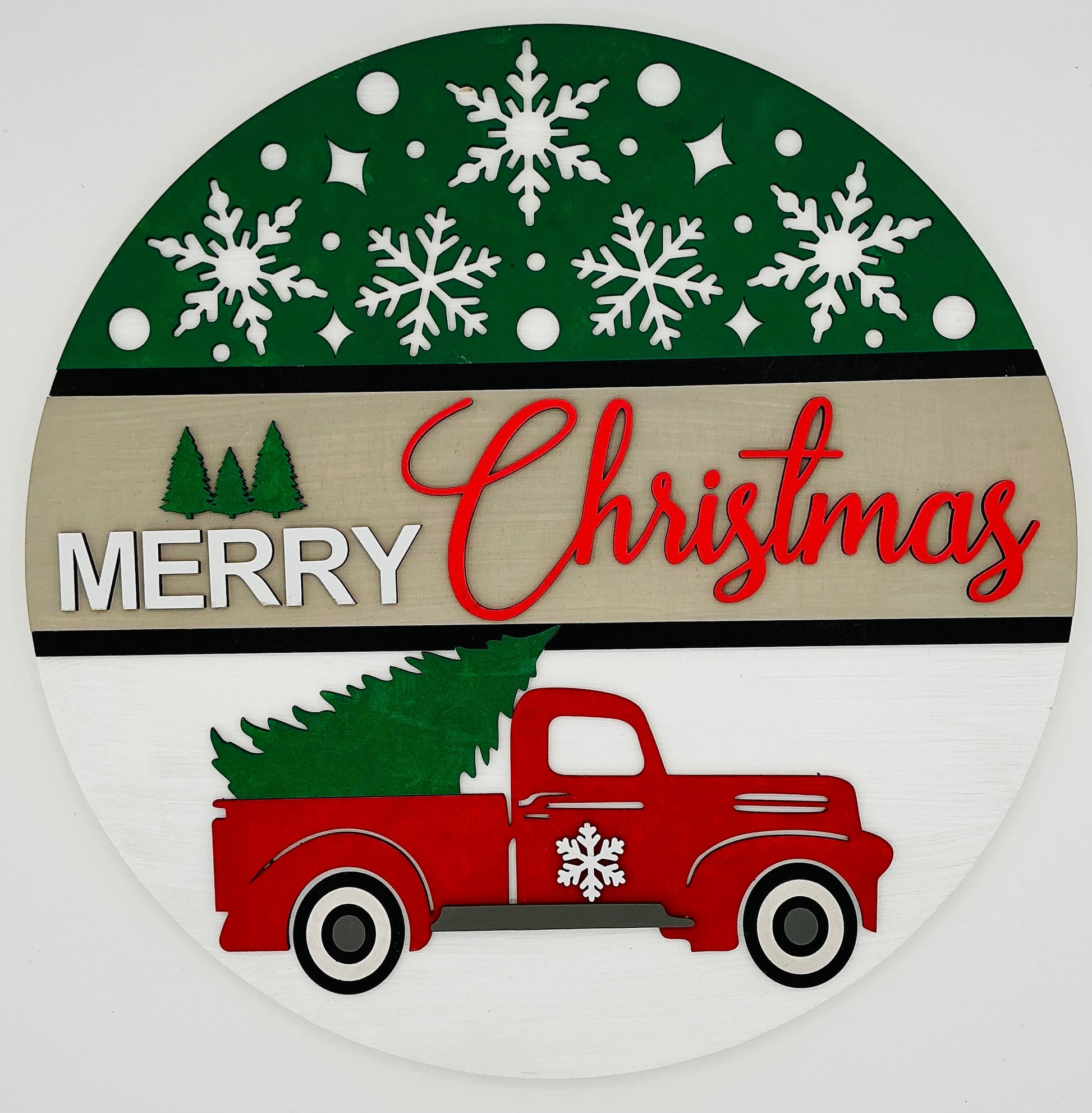 Decorative Christmas sign with a red truck carrying a Christmas tree, surrounded by snowflakes on a green and beige background.