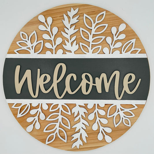 Round wooden sign with white leaf patterns and the word 'Welcome' on a gray background