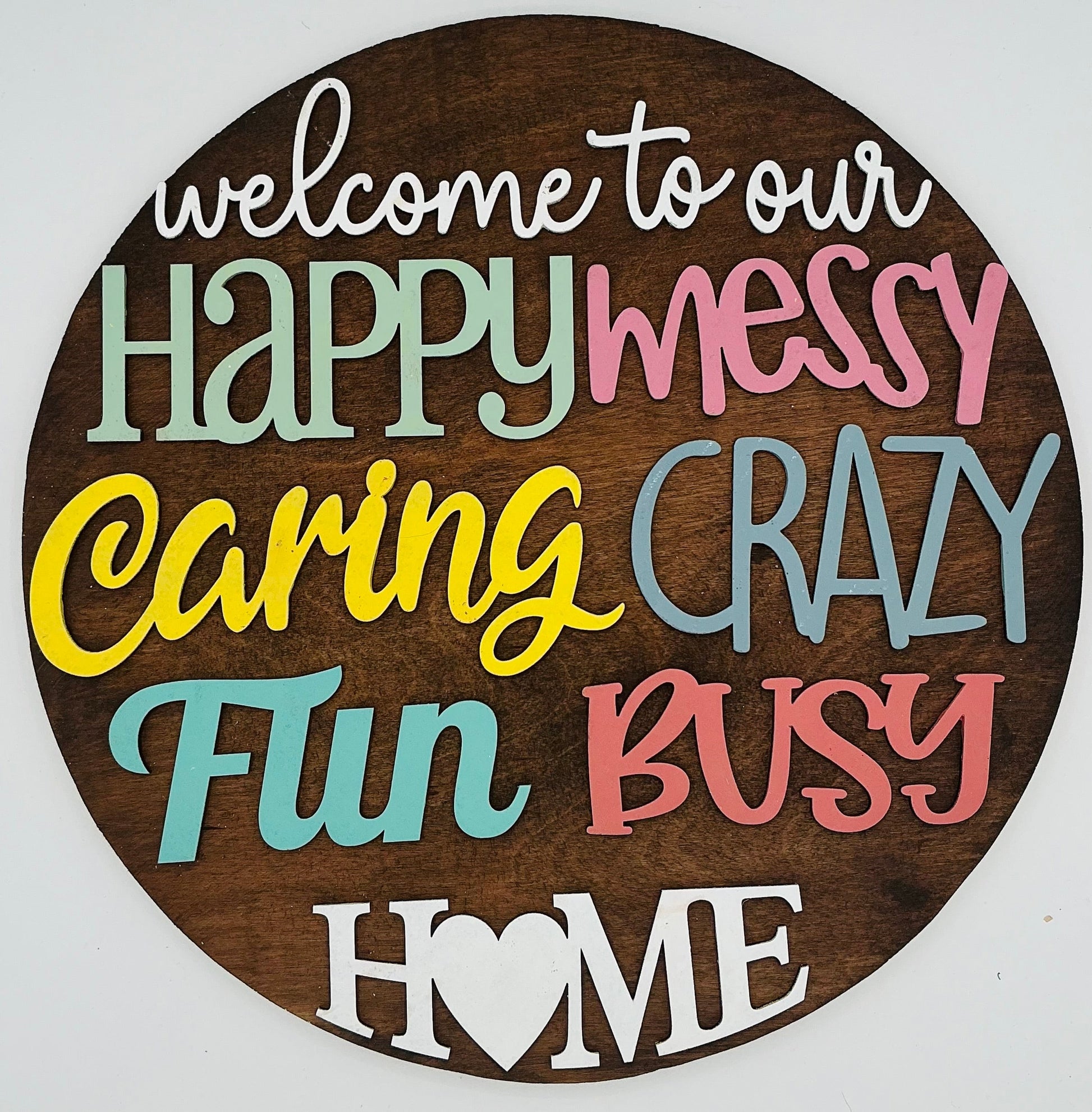 Round wooden sign with colorful text on a white background