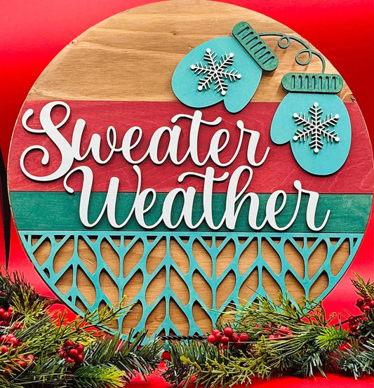 Decorative sign with 'Sweater Weather' text, snowflake designs, and Christmas elements on a red background.