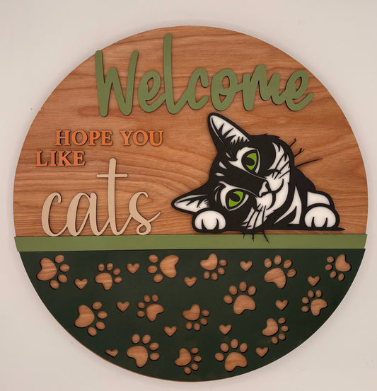 Wooden circular sign with a cat illustration and text 'Welcome, hope you like cats' on a white background.