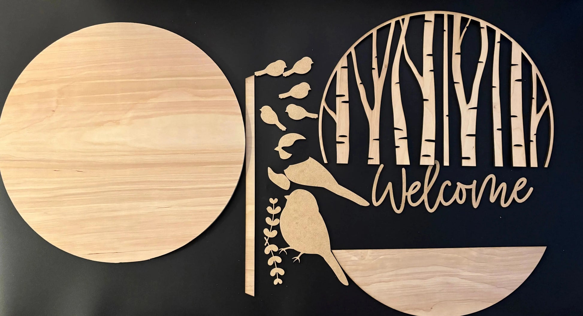 Wooden cutout with 'Welcome' text and nature-themed design on a black background