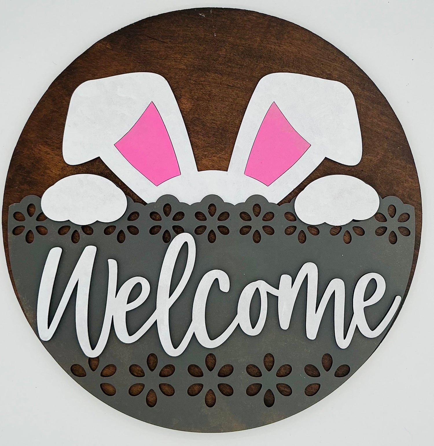 Decorative sign with bunny ears and 'Welcome' text on a wooden background