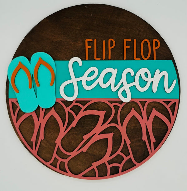 Decorative sign with 'Flip Flop Season' text and flip flop designs on a brown background.