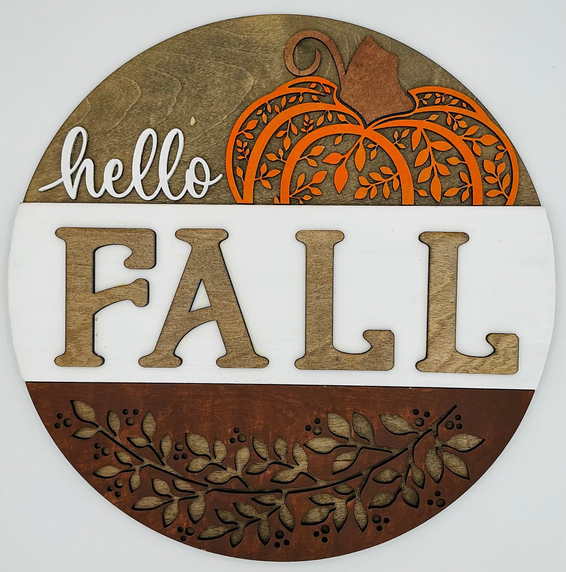 Round wooden sign with 'hello FALL' text and pumpkin design on a white background