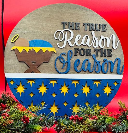 Decorative sign with nativity scene and 'The True Reason for the Season' text on a red background.