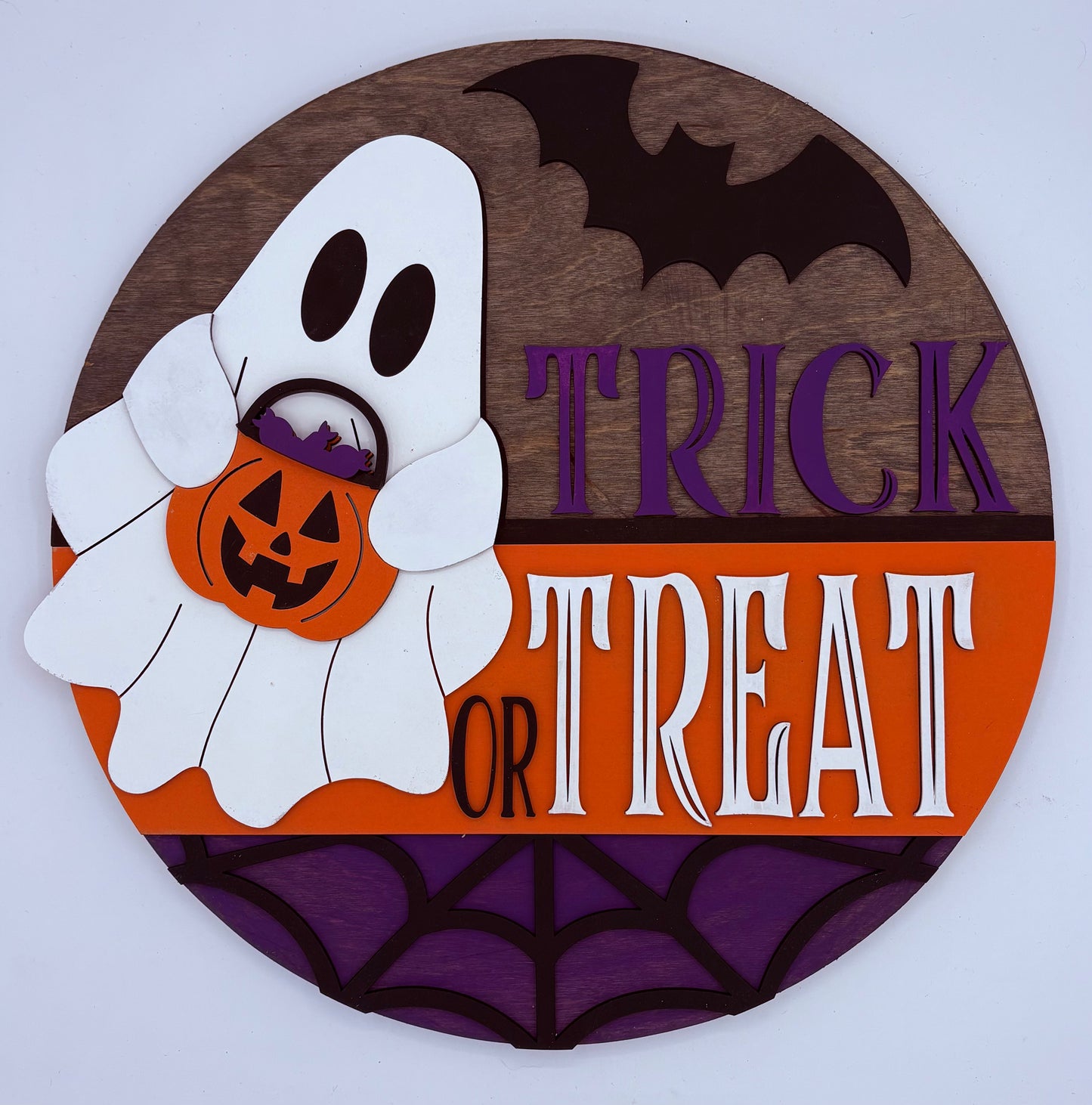 Halloween-themed decorative sign with ghost, pumpkin, and 'Trick or Treat' text on a wooden background.