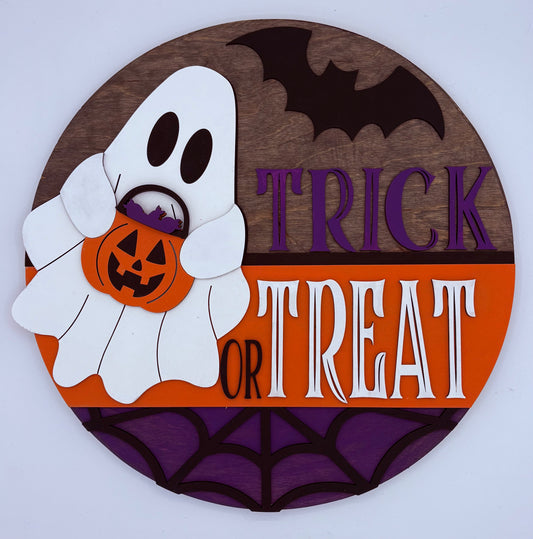 Halloween-themed decorative sign with ghost, pumpkin, and 'Trick or Treat' text on a wooden background.