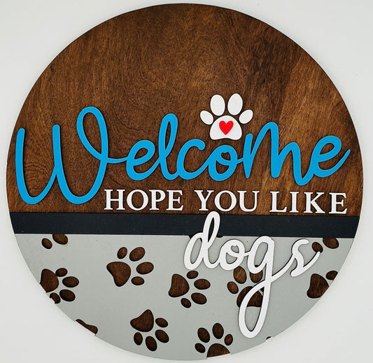 Round wooden sign with 'Welcome Hope You Like Dogs' text and paw prints on a white background