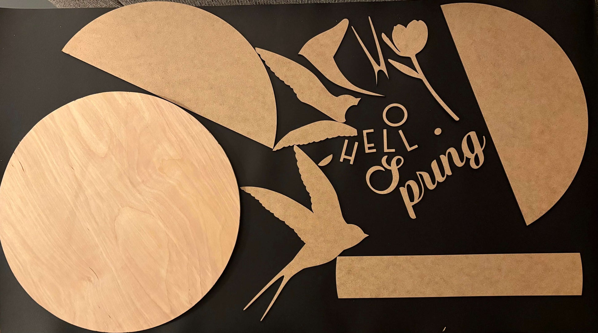 Cardboard cutouts of a bird, tulip, and text on a black background
