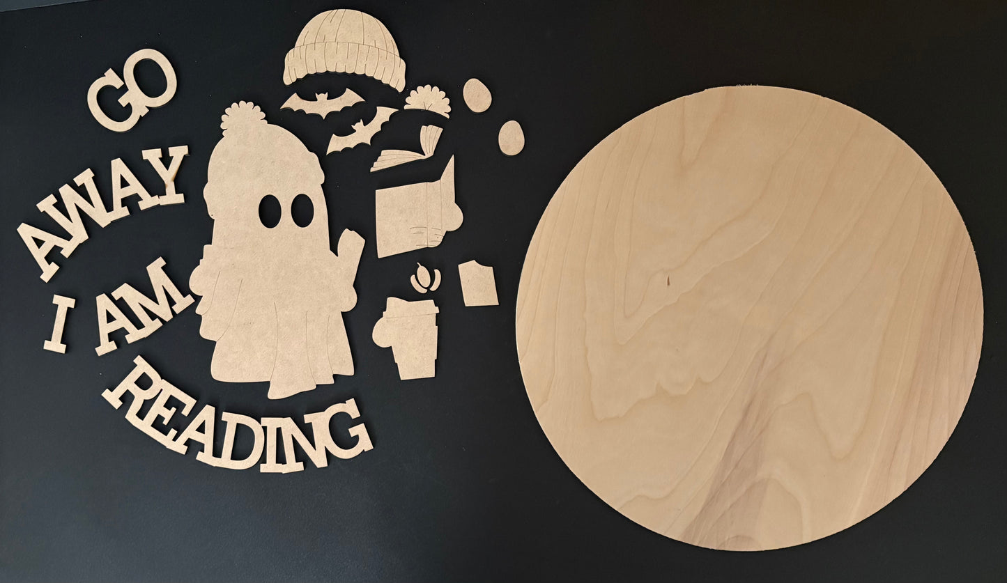 Wooden cutout with text 'Go Away I Am Reading' next to a round wooden board on a black background