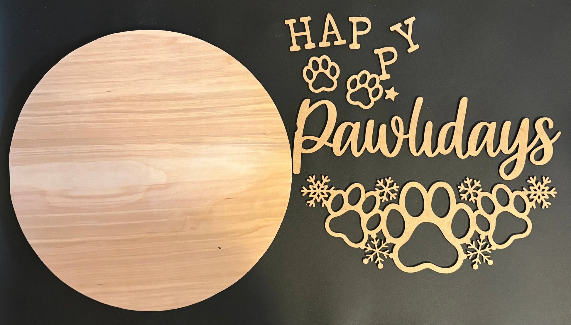 Wooden circular board with 'Happy Pawlidays' text and paw prints on a dark background