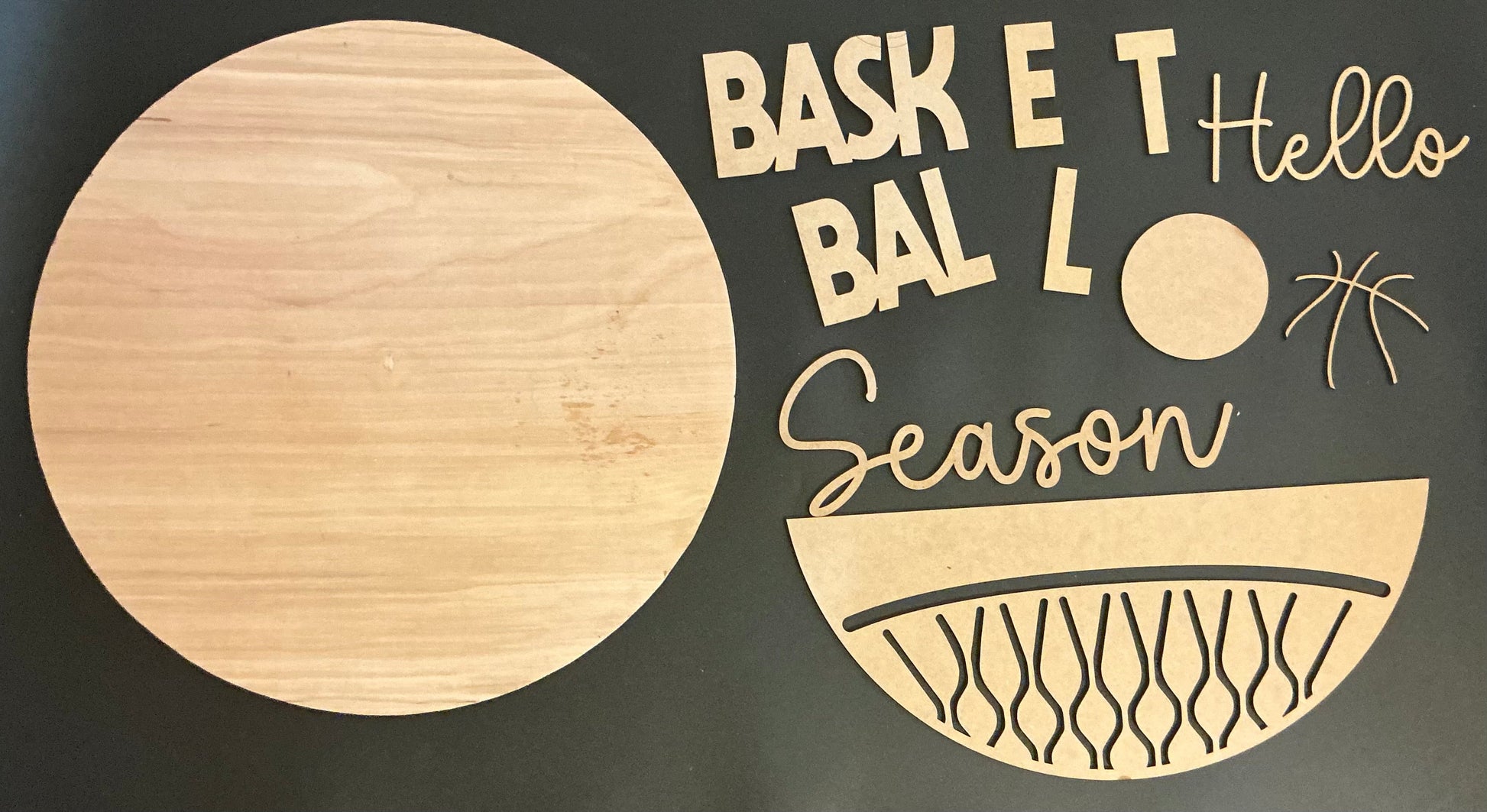 Wooden cutout of a basketball with decorative text on a dark background