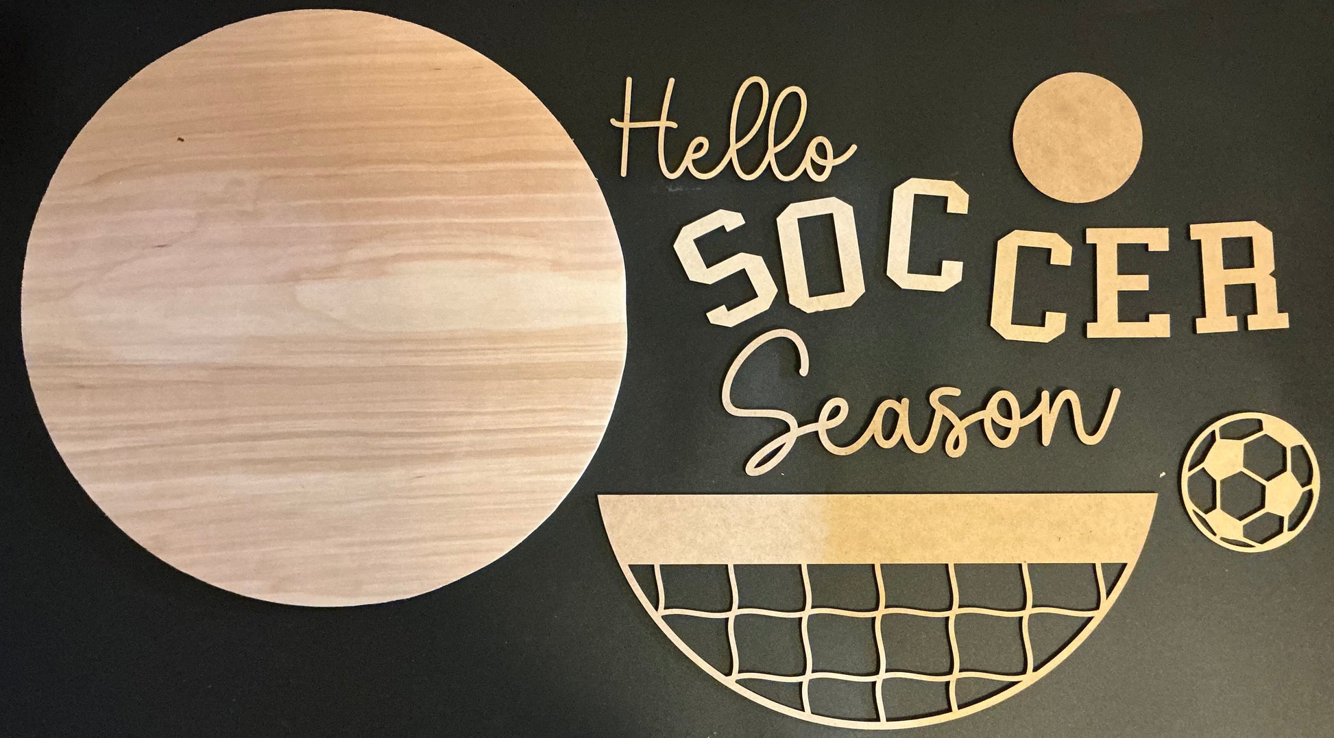 Wooden cutout letters spelling 'Hello Soccer Season' on a black background