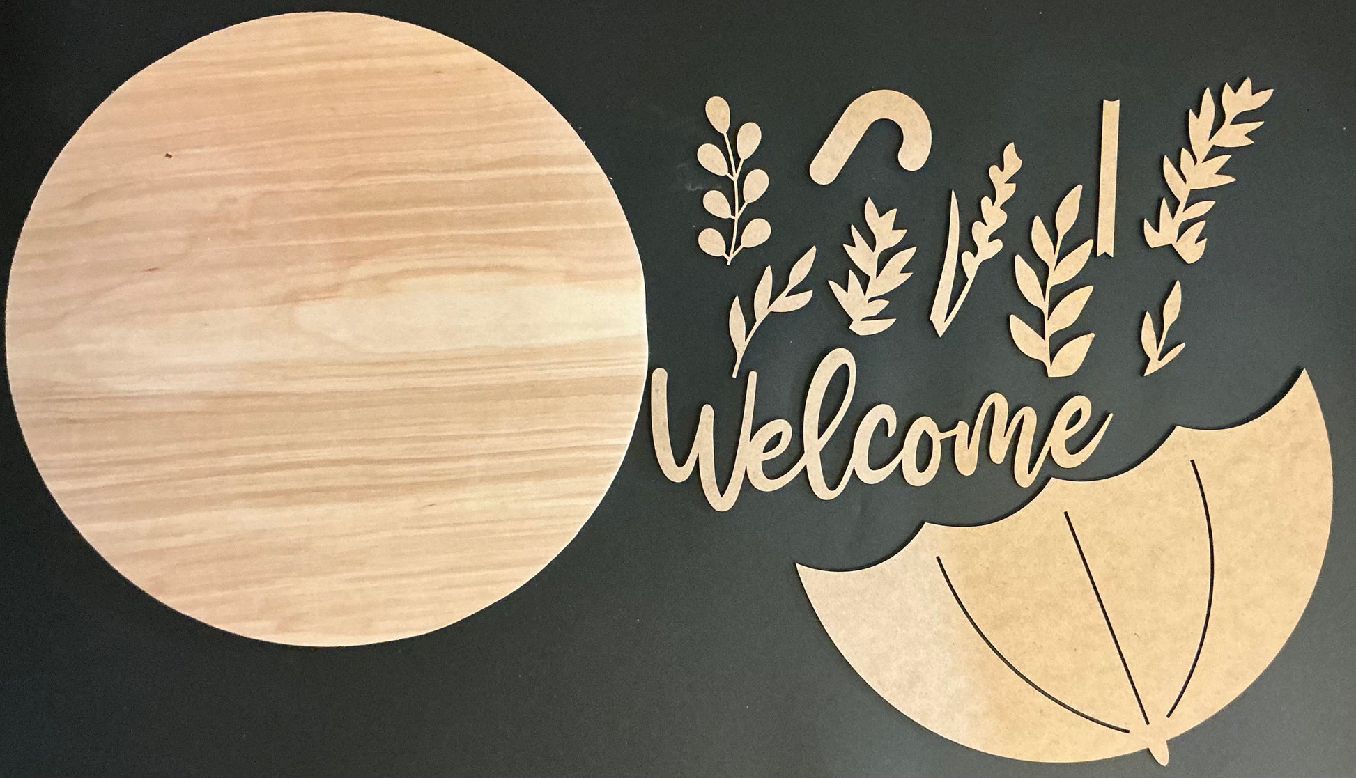 Wooden decorative cutout with 'Welcome' text and leaf designs on a black background